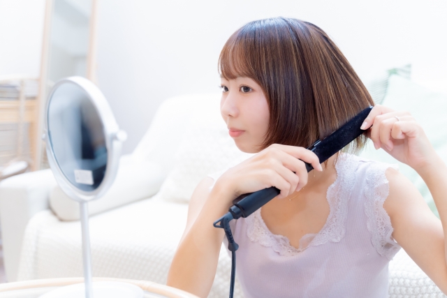鏡を見ながらアイロンをする女性